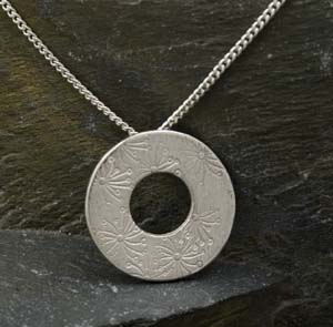 Silver round washer type pendant with stamped flower design