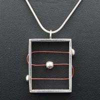Oblong silver pendant with red wire design feature